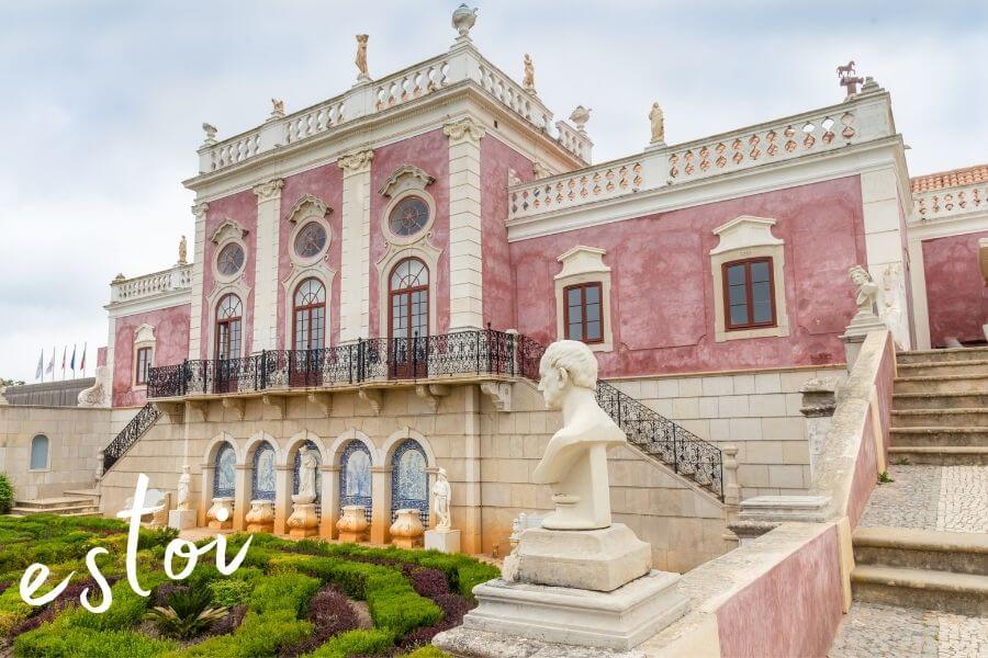 The historic Pousada Palacio de Estoi, a pink palace surrounded by green gardens in Estoi, Portugal.