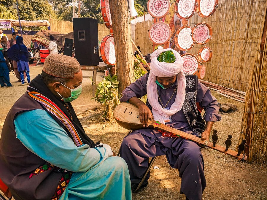 Two men play traditional Pakistani Balochi music on a wooden sitar.
