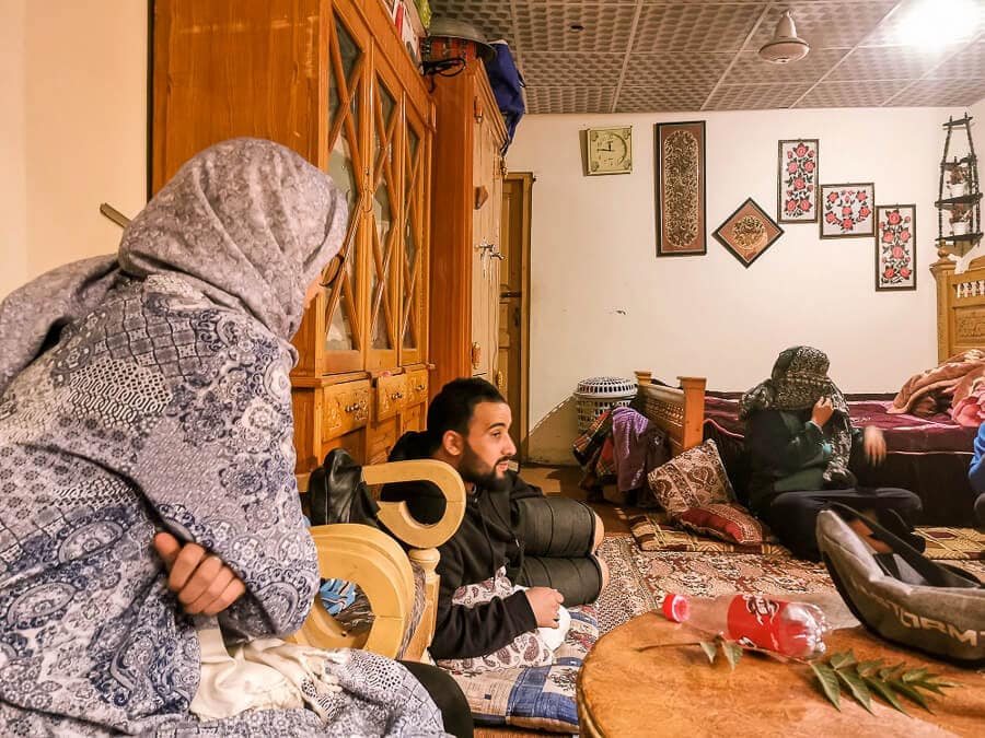 A group of people sit and talk in a typical Pakistani living room in the city of Skardu.