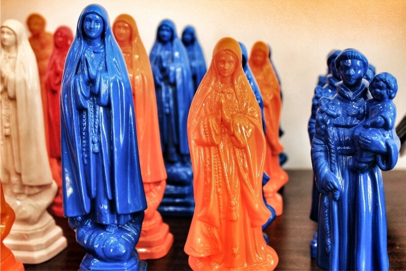 Blue and orange statues of Our Lady of Fatima for sale at a souvenir shop in Lisbon.