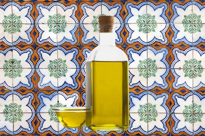 A bottle of olive oil against a backdrop of colourful Portuguese tiles.