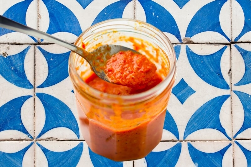 A jar of chunky peri-peri sauce against a backdrop of colourful Portuguese tiles.