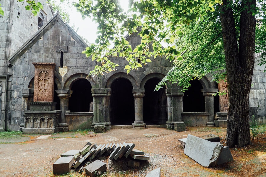 Sanahin Monastery in Armenia, a grey stone monastery with arched cloisters and a leafy tree out front.