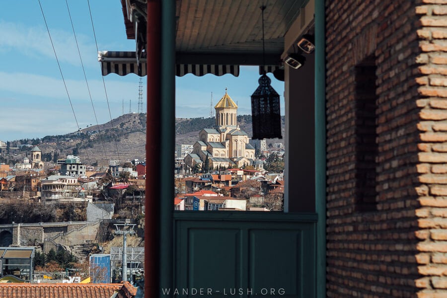 A view of Tbilisi with a large church framed by a balcony.