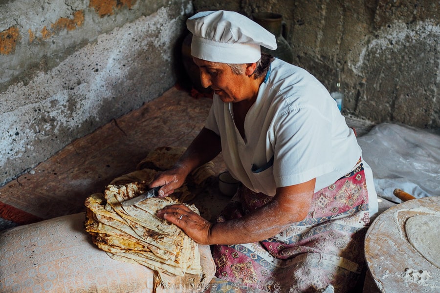 A woman makes lavash bread in a traditional oven, a must-see on any Armenia itinerary.