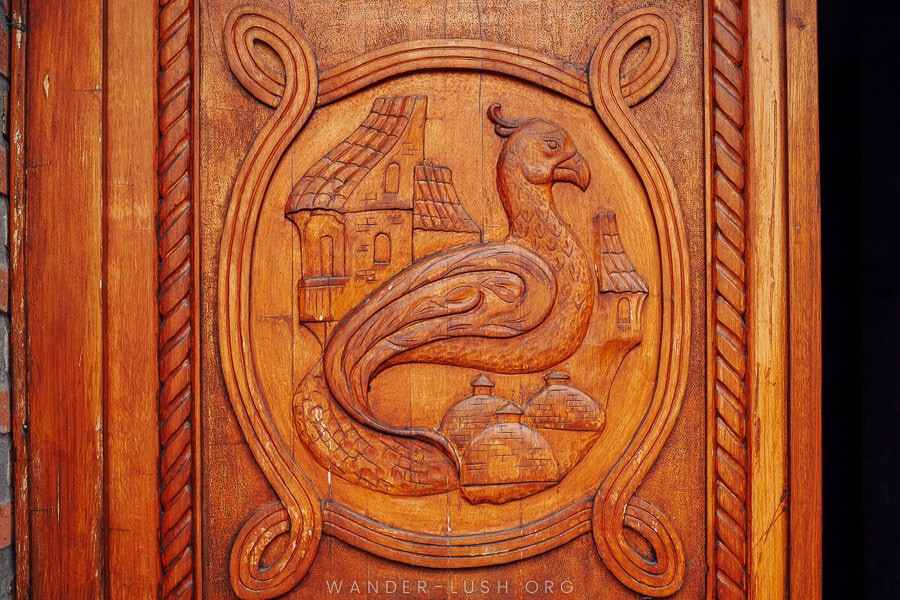 A carved wooden door in Abanotubani depicts a falcon bird and the domed roofs of the Tbilisi sulphur baths.