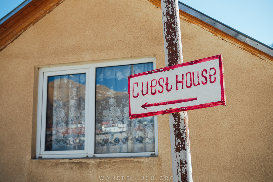 A handpainted sign points towards a guesthouse in Kazbegi.