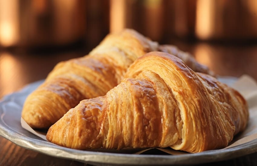 Golden brown croissants arranged on a plate.