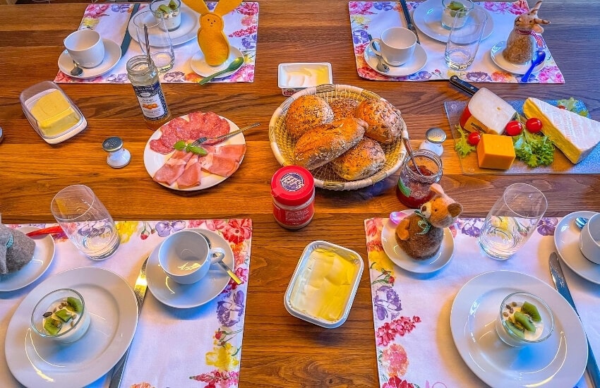 A table spread with bread rolls, cheeses and cold meats.