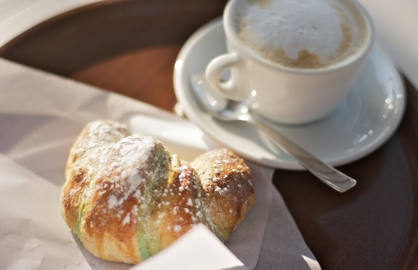 A cornetto pastry and a cup of coffee for breakfast in Italy.
