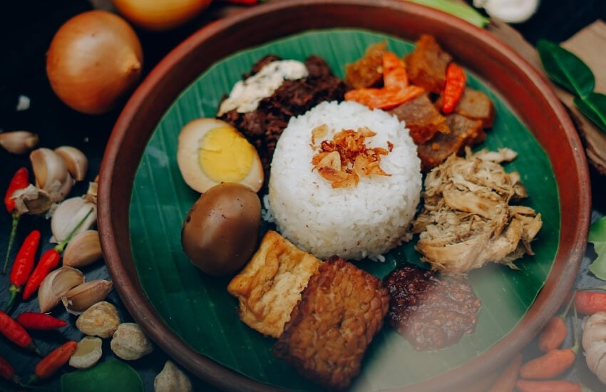 Nasi Lemak, an arrangement of rice, meats and eggs on a banana leaf.