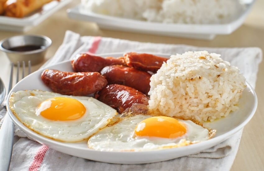 Red sweet longganisa sausages served with fried eggs and rice for breakfast in the Philippines.