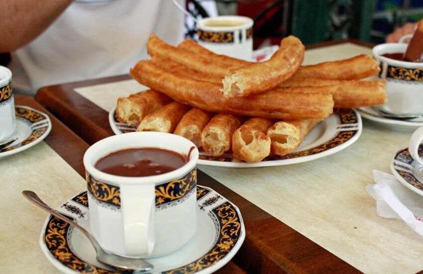 Churros and chocolate arranged on a cafe table in Spain.