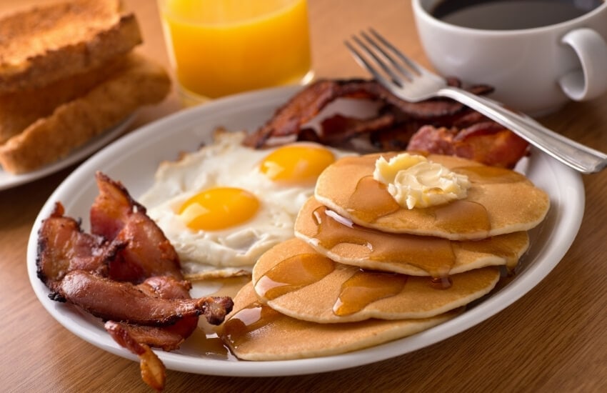 Pancakes served with eggs and bacon.