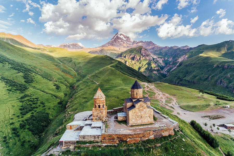 Aerial view of Gergeti Trinity Church against a backdrop of mountains - a must-see when you visit Kazbegi, Georgia.