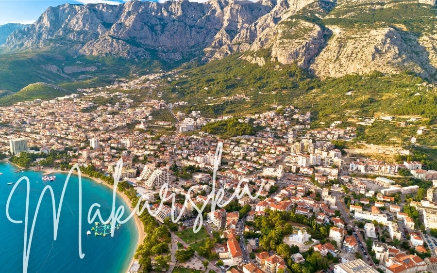 Makarska, a beautiful Croatian town set beneath dramatic mountain peaks in front of a blue-water bay.