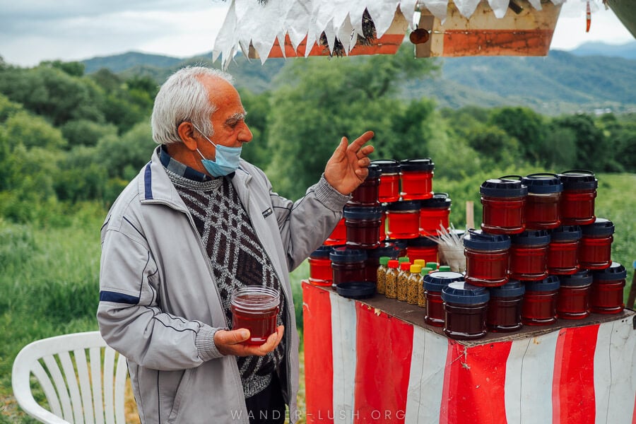 A man sells plastic pots of honey from a roadside stall in Georgia.