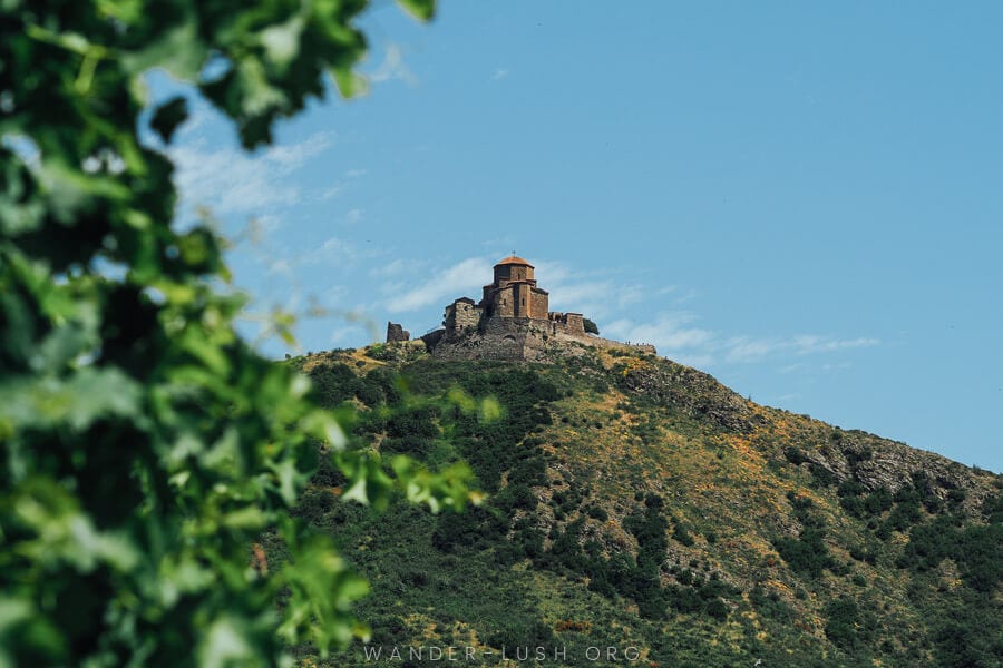 View of Georgia's Jvari Monastery atop a green hill.