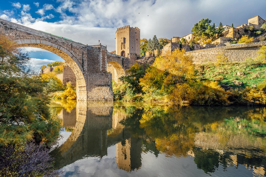 A Roman stone arched bridge spans the river Targus in Toledo, Spain.