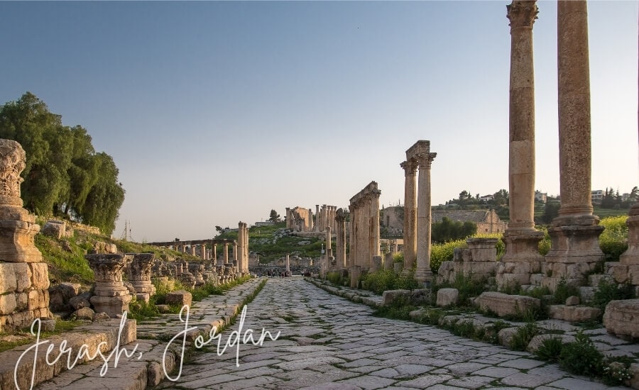 A stone path leads through a row of tall columns at the Jerash Ruins in Jordan.