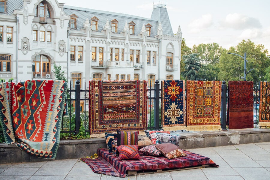 Caucasian carpets hang on a fence in front of a historic building in the city centre of Tbilisi.