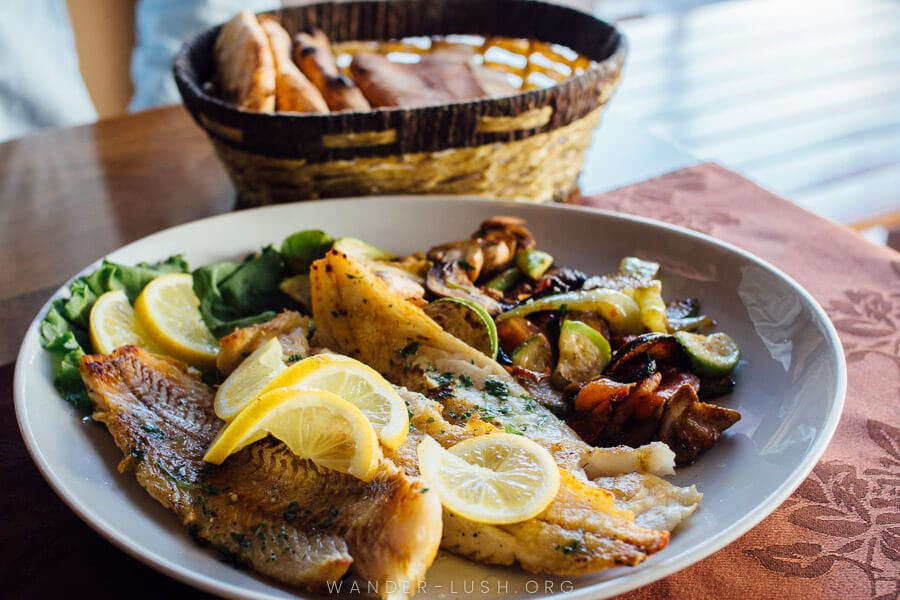 A plate of fresh fish and grilled vegetables at a restaurant in Montenegro.