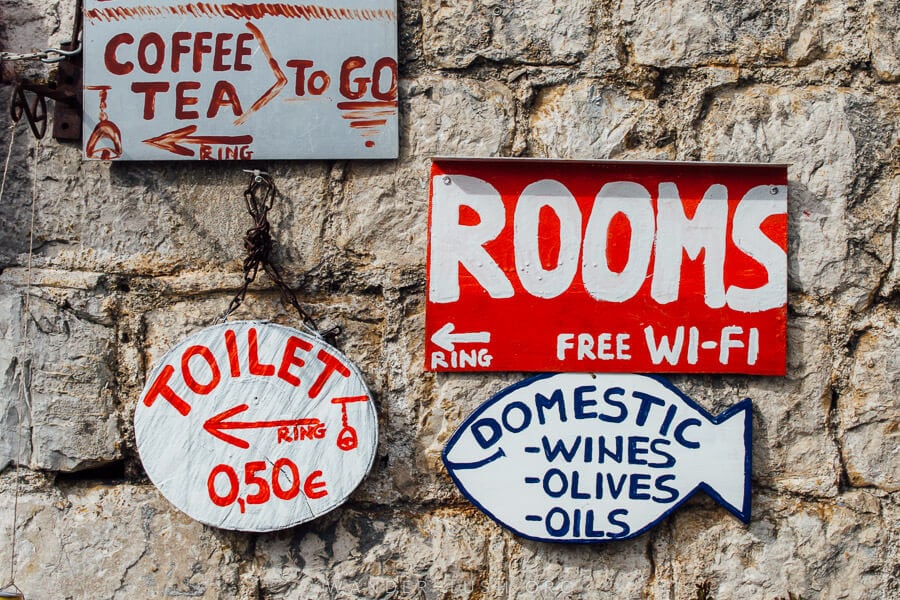 Signs point to guesthouses and cafes in Perast, Montenegro.