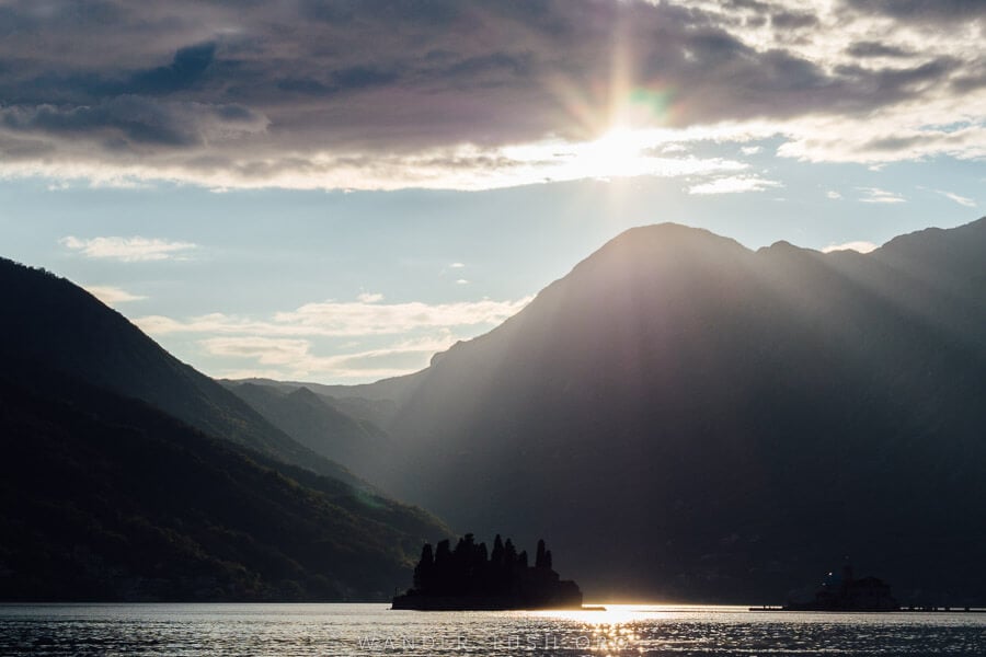 The sun sets on the Bay of Kotor over a small island in Perast, Montenegro.