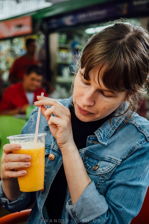 A woman drinks fresh juice at a market in Medellin.