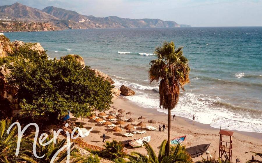 Palm trees and beach umbrellas in the seaside town of Nerja, Spain.