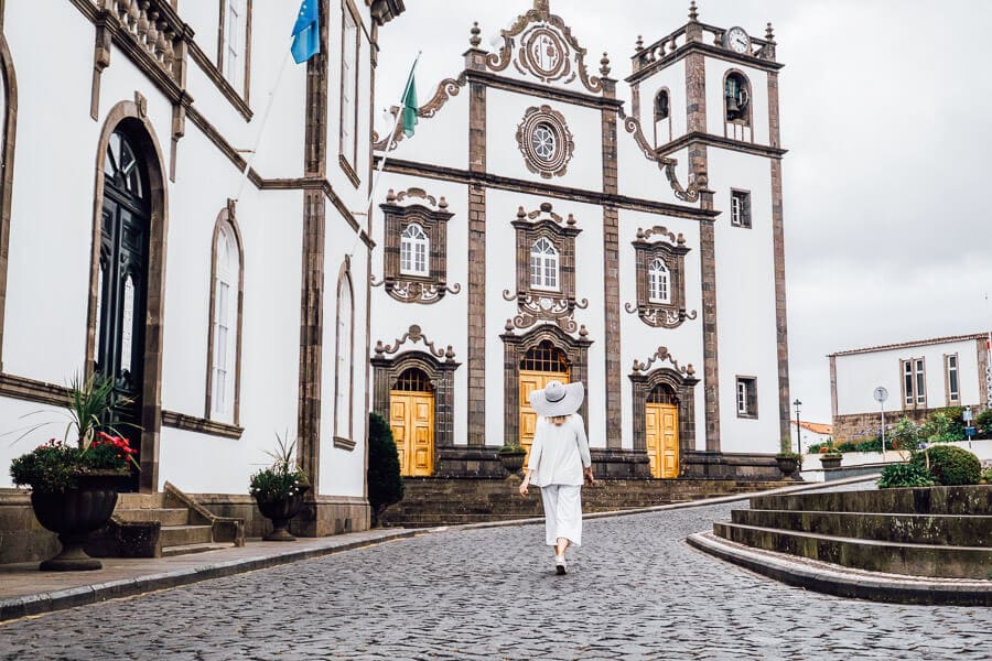 A woman dressed in white walks amongst beautiful stone architecture in the Portuguese island city of Ponta Delgada.