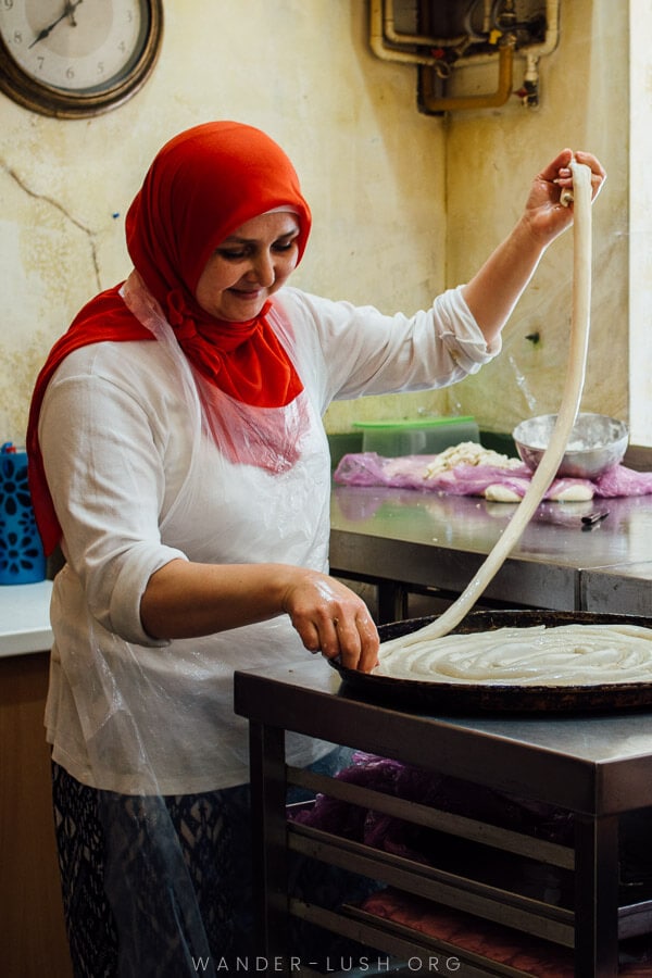 A woman coils burek dough into a round pan at a bakery in Sarajevo.