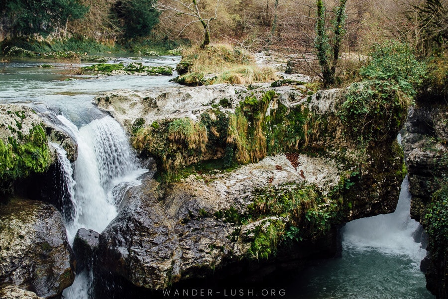 A small waterfall cascades over black rocks at Martvili in Georgia.