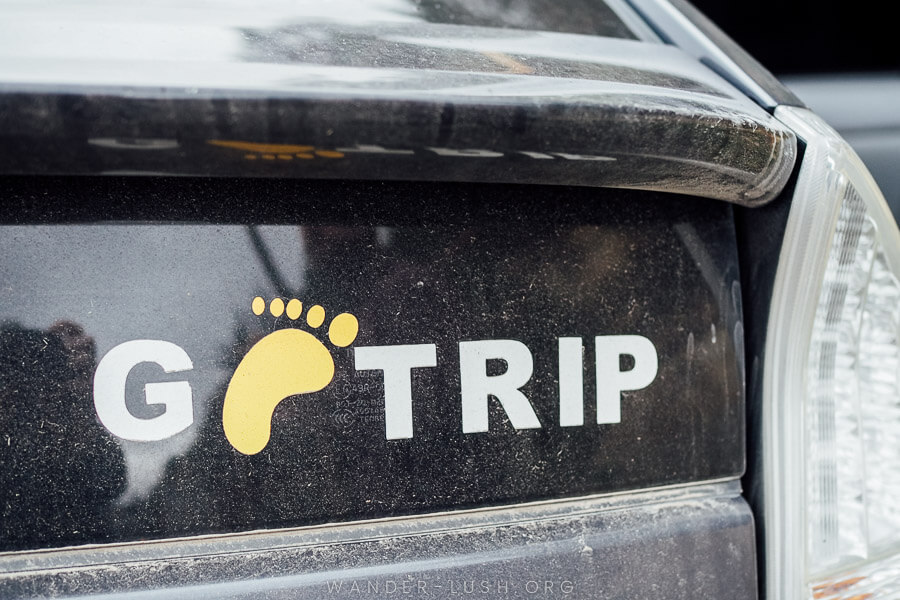 A dusty car with a bumper sticker that says GoTrip.