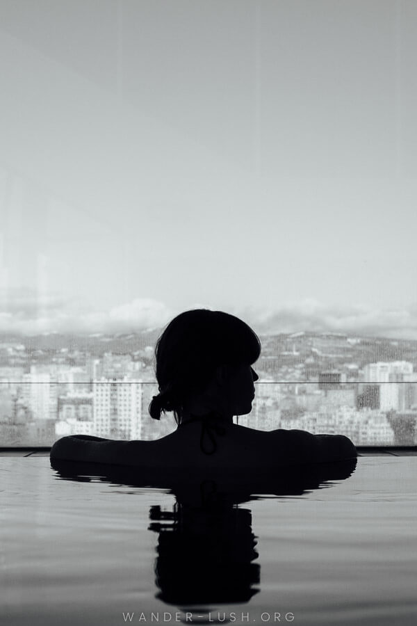 A woman looks out the window from inside the pool at Radisson Blu Iveria hotel.