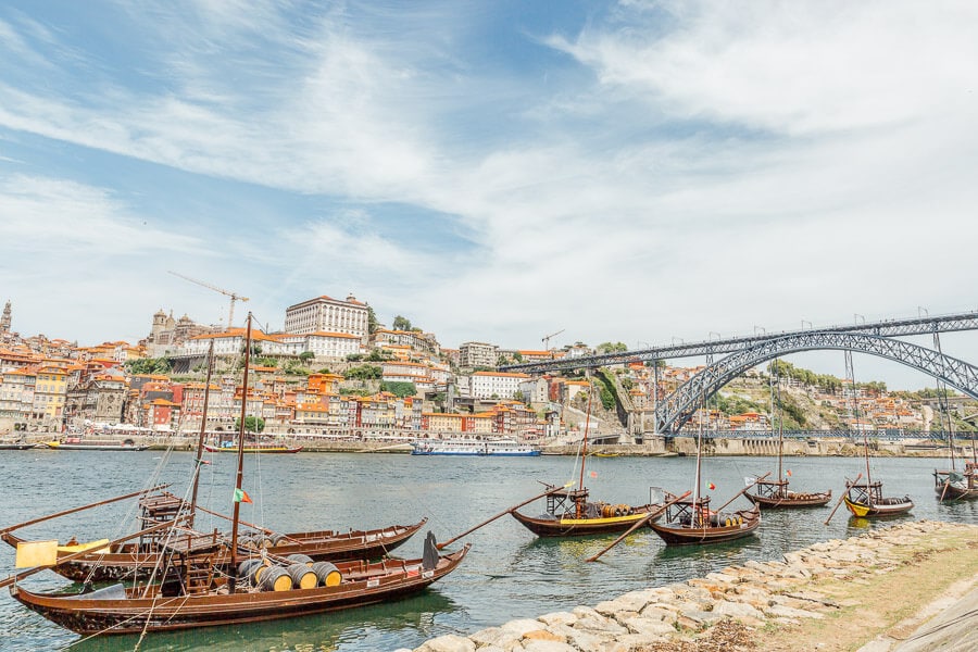 A fleet of rabelo boats on the river in Porto, with a beautiful bridge in the background.