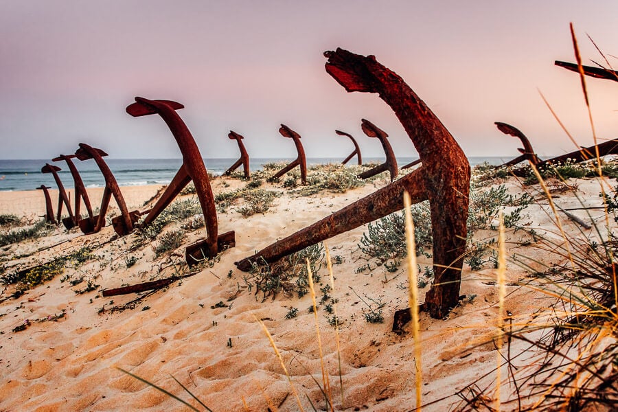 Rusty anchors lying on the beach on Tavira Island, one of the most offbeat things to do in Portugal.