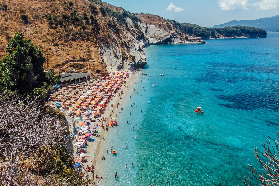 People swim in blue water at Mirror Beach in Albania.
