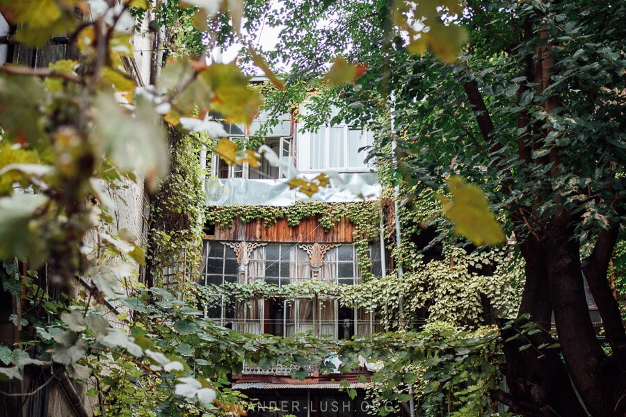 A leafy courtyard and wooden balcony in Tbilisi, Georgia.