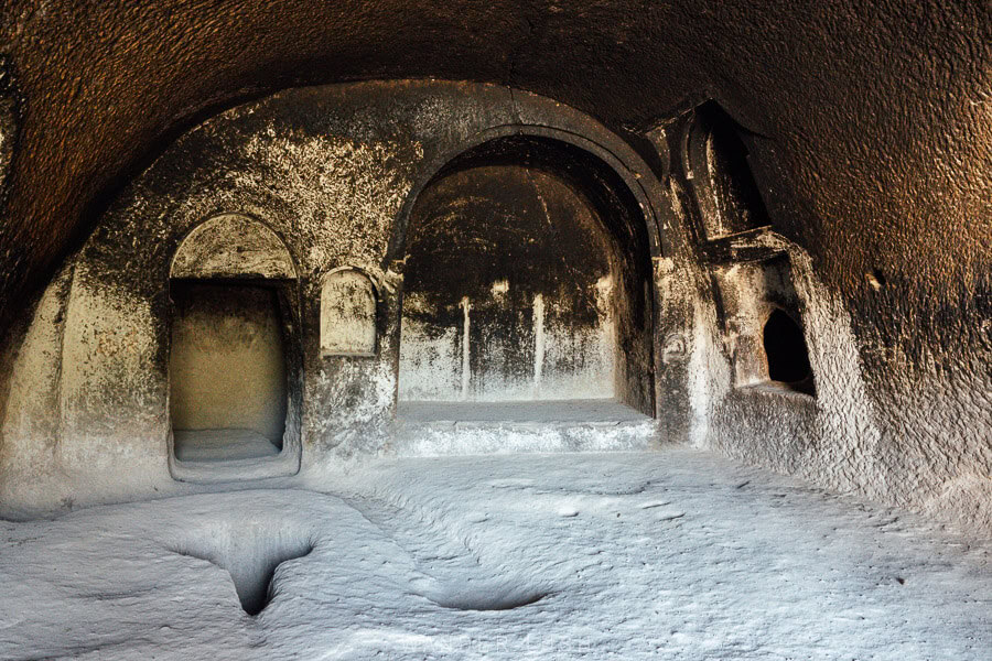 The interior of a cave at Vardzia, with bread ovens carved from the stone floor and blacked walls from smoke.
