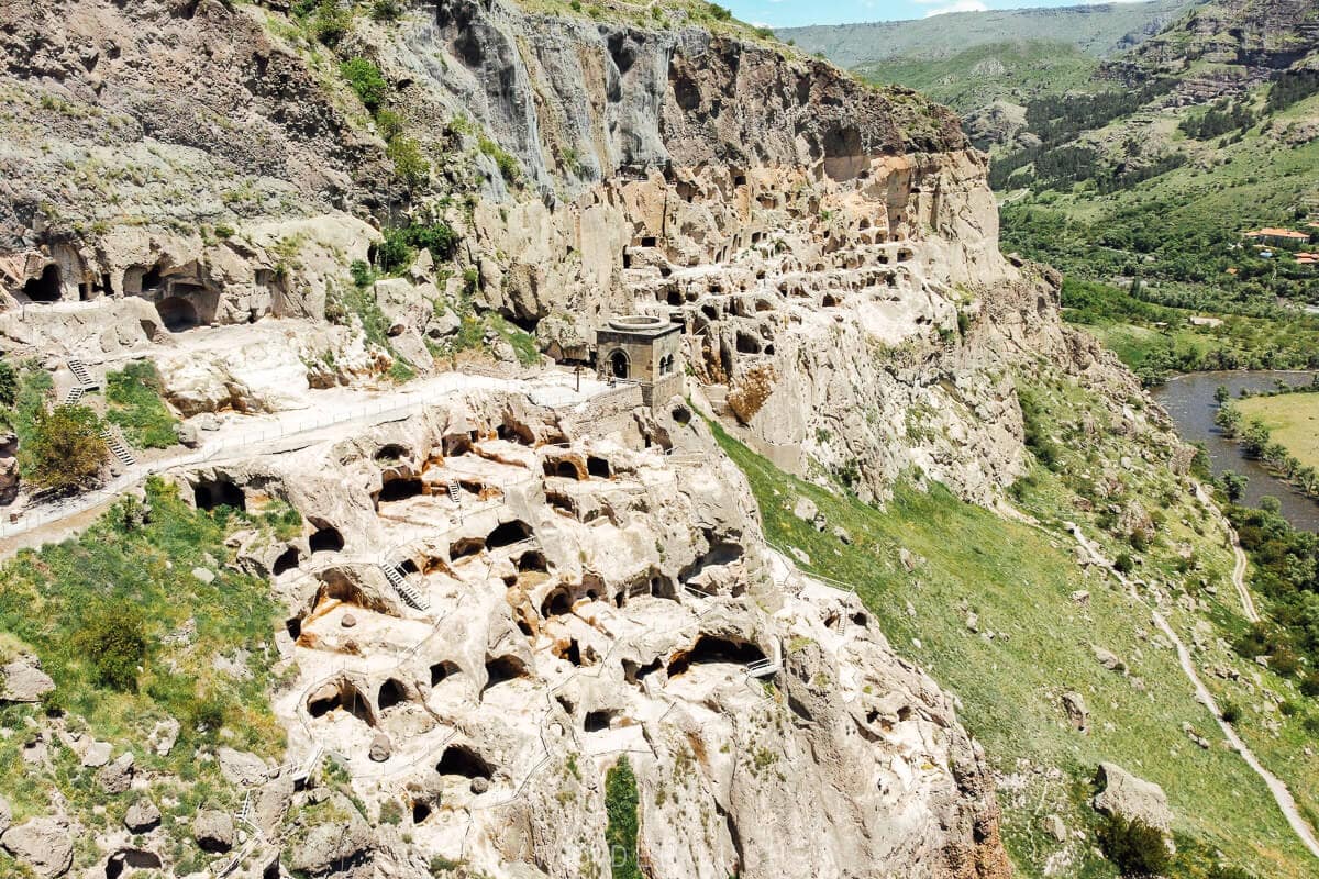 An aerial drone photo of Vardzia cave city, a series of chambers hewn from the rocky cliffs above the Mtkvari River in Georgia.