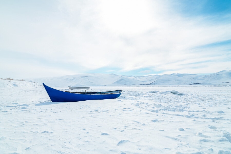 A blue boat parked in the snow and ice on a frozen Lake Cildir in Turkey.