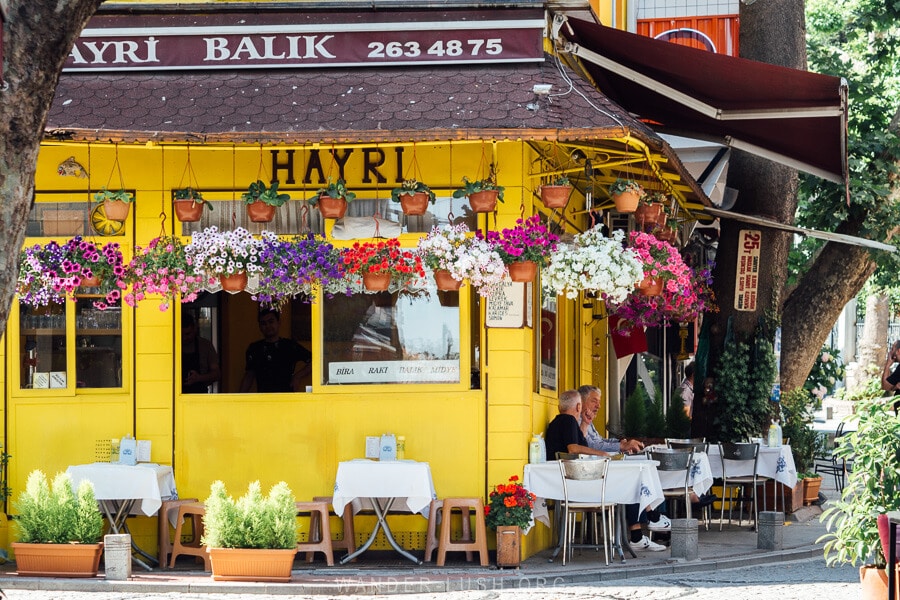 A bright yellow Istanbul restaurant with white tableclothed tables out front.
