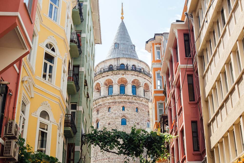 Istanbul's Galata Tower, viewed from a narrow street in between colourful apartment buildings.