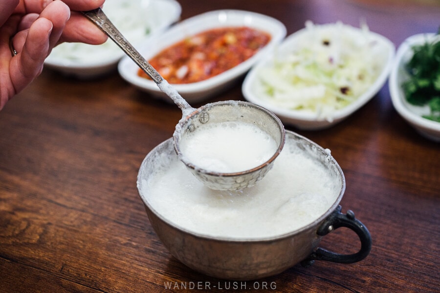 A silver cup of ayran, a creamy yogurt drink served with a round spoon at a restaurant in Istanbul, Turkey.