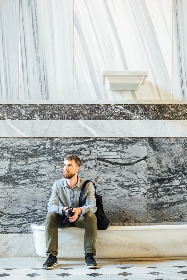 A man sits in front of a marble wall inside Salt Galata, an arts space on Banks Street in Istanbul, Turkey.