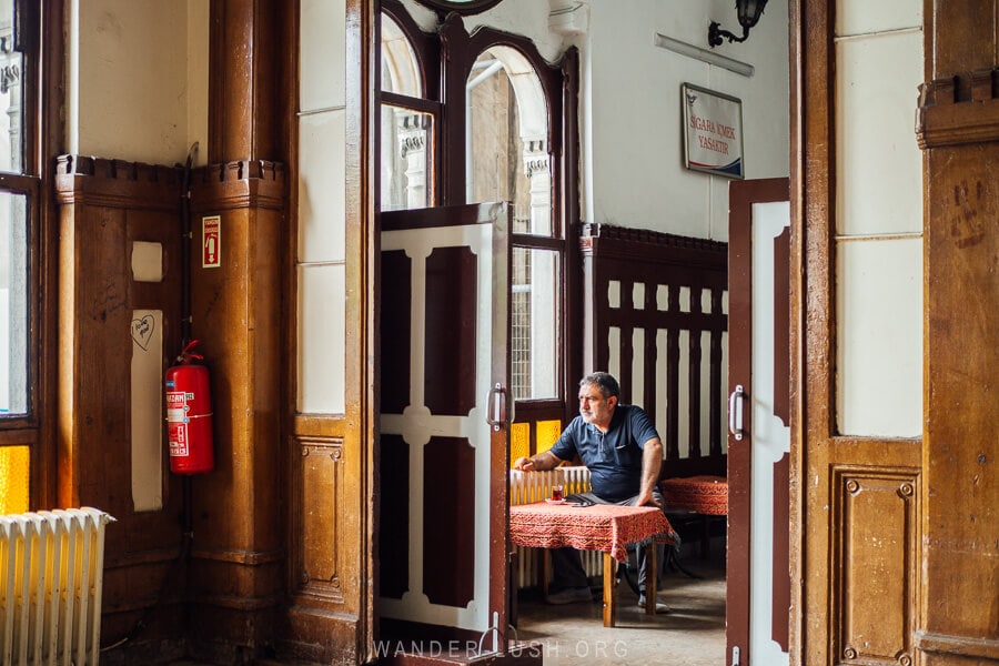A man sits alone at Sirkeci Train station sipping a glass of cay tea.
