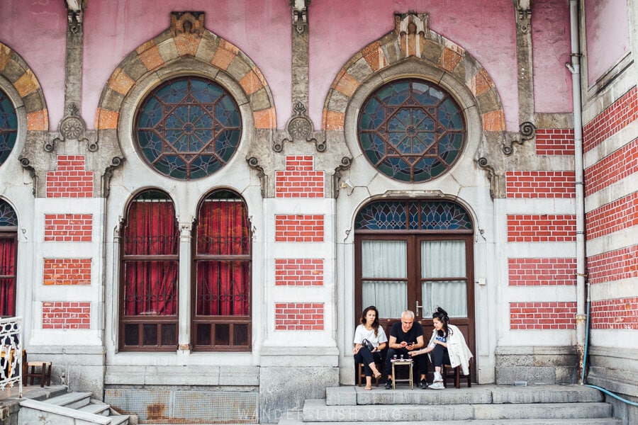 Three people sit at a table drinking tea in front of Istanbul historic Sirkeci Train Station.