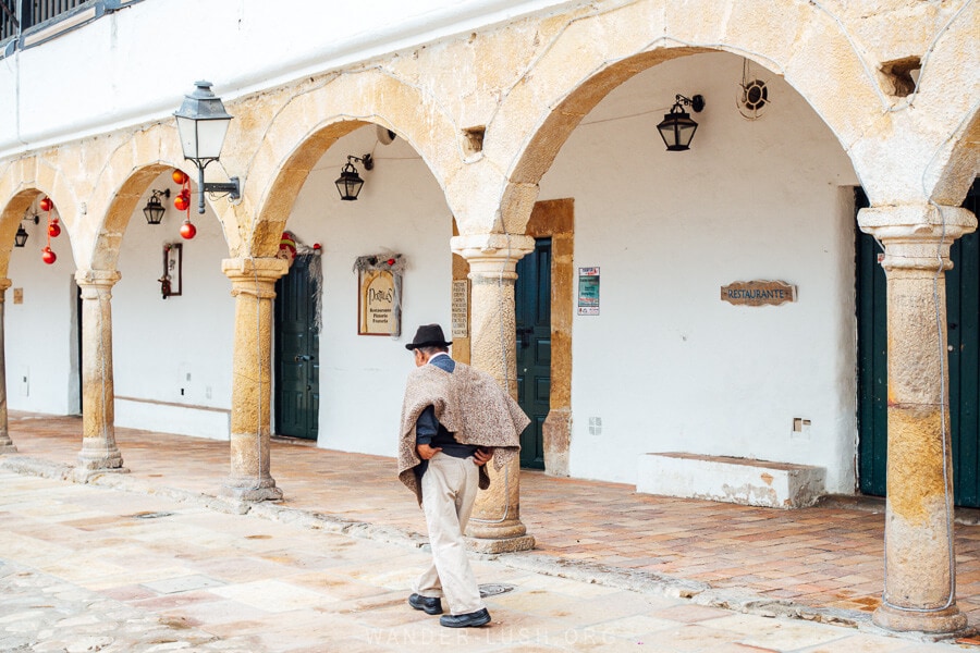 A Colombian man in a poncho walks past stone arches in the colonial town of Villa de Leyva near Bogota.