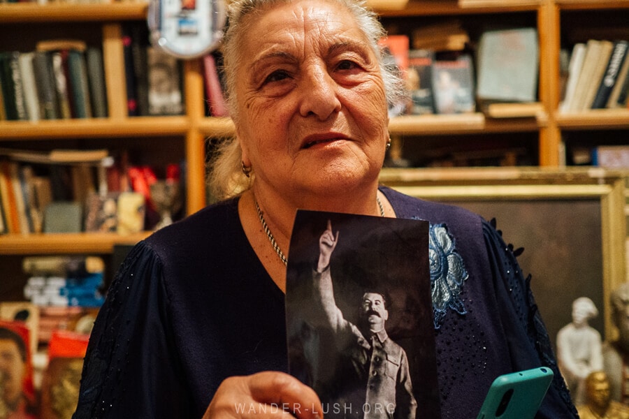 An elderly Georgian woman holds up a black and white photograph of Joseph Stalin inside her house museum in Gori.